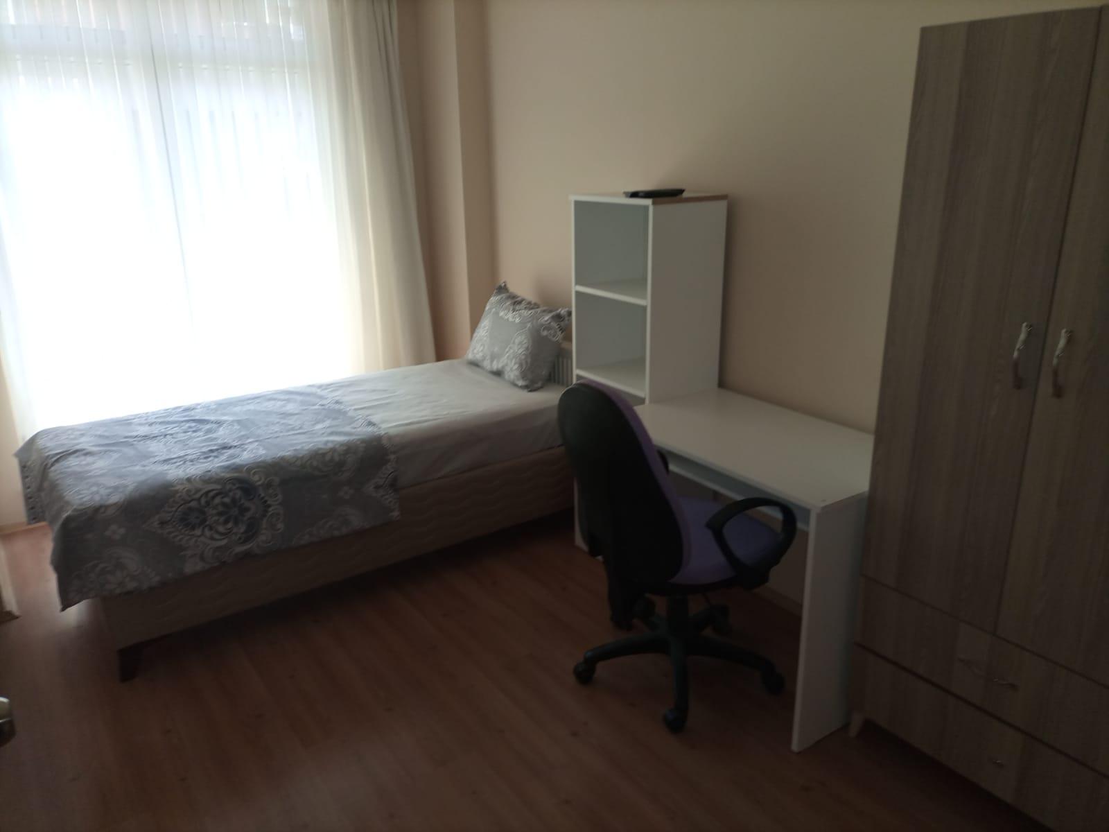 Tek kişilik oda, yatak ve çalışma sandalyesi